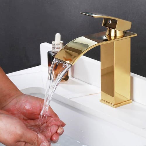 Torneira dourada de luxo com água corrente em cuba de banheiro