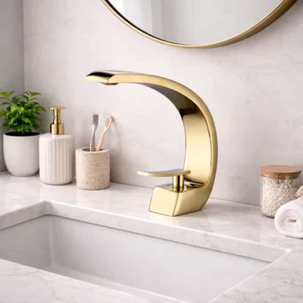 Torneira de lavatório banhado em ouro curvada, luxuosa, para banheiro, com alavanca e bico curvo, em uma bancada de mármore branco.